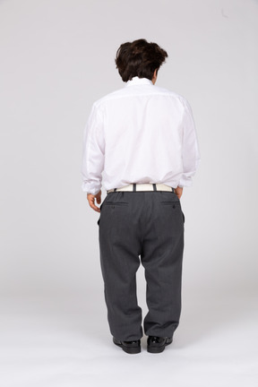 Young man in shirt and trousers facing away from camera