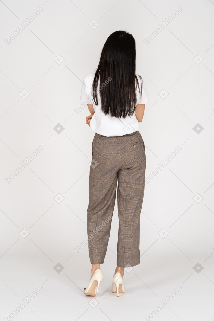 Back view of a displeased young lady in breeches and t-shirt crossing hands
