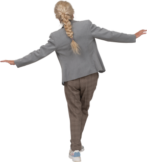 Vista posterior de una anciana en traje de pie con los brazos extendidos