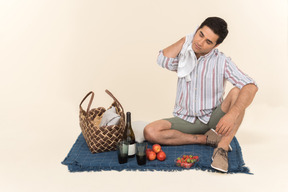 Junger kaukasischer mann, der auf der decke sitzt und seinen stutzen mit tuch trocknet