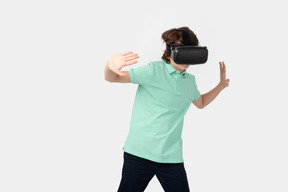 가상의 벽을 만지는 vr 헤드셋을 쓴 소년