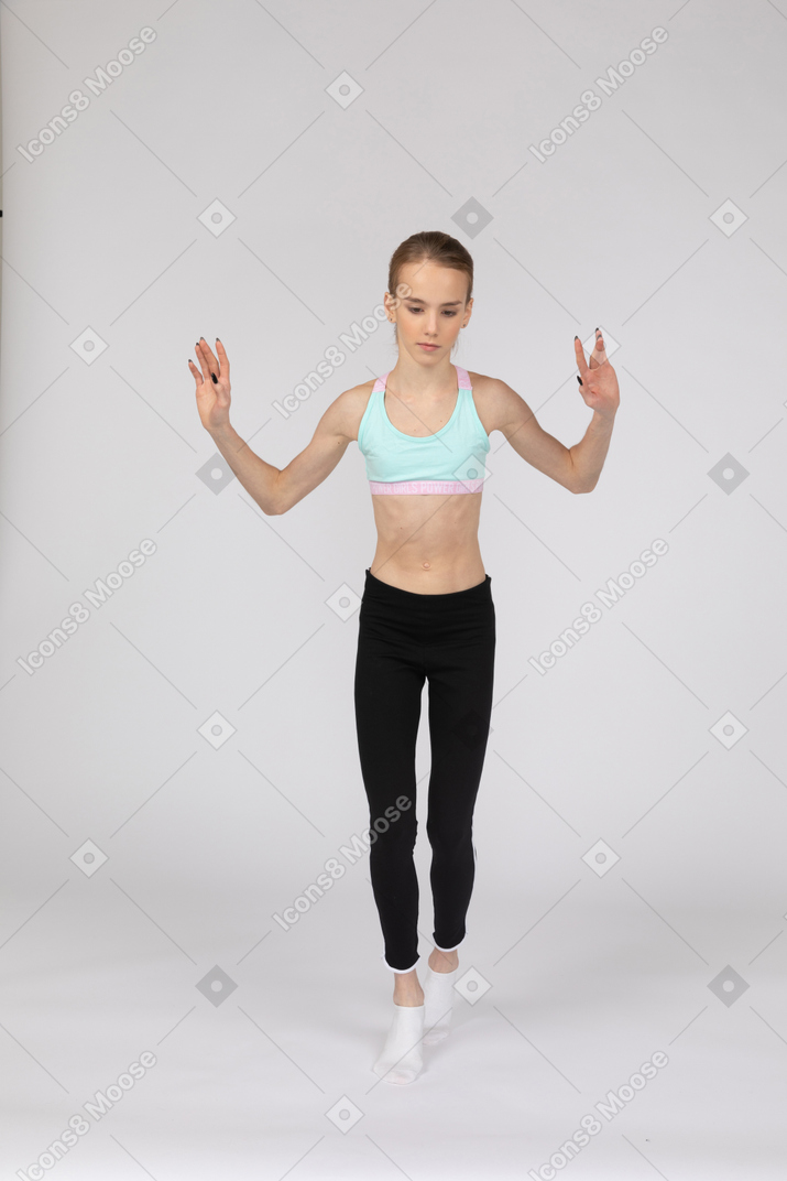 Vue de face d'une adolescente en tenue de sport marchant prudemment sur la pointe des pieds