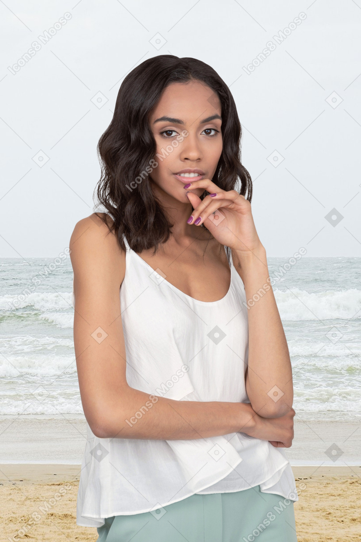 A beautiful young woman standing on top of a sandy beach