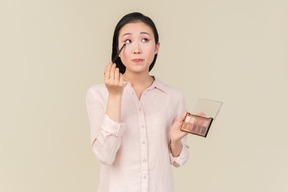 年轻的亚洲女人专注于眼影应用