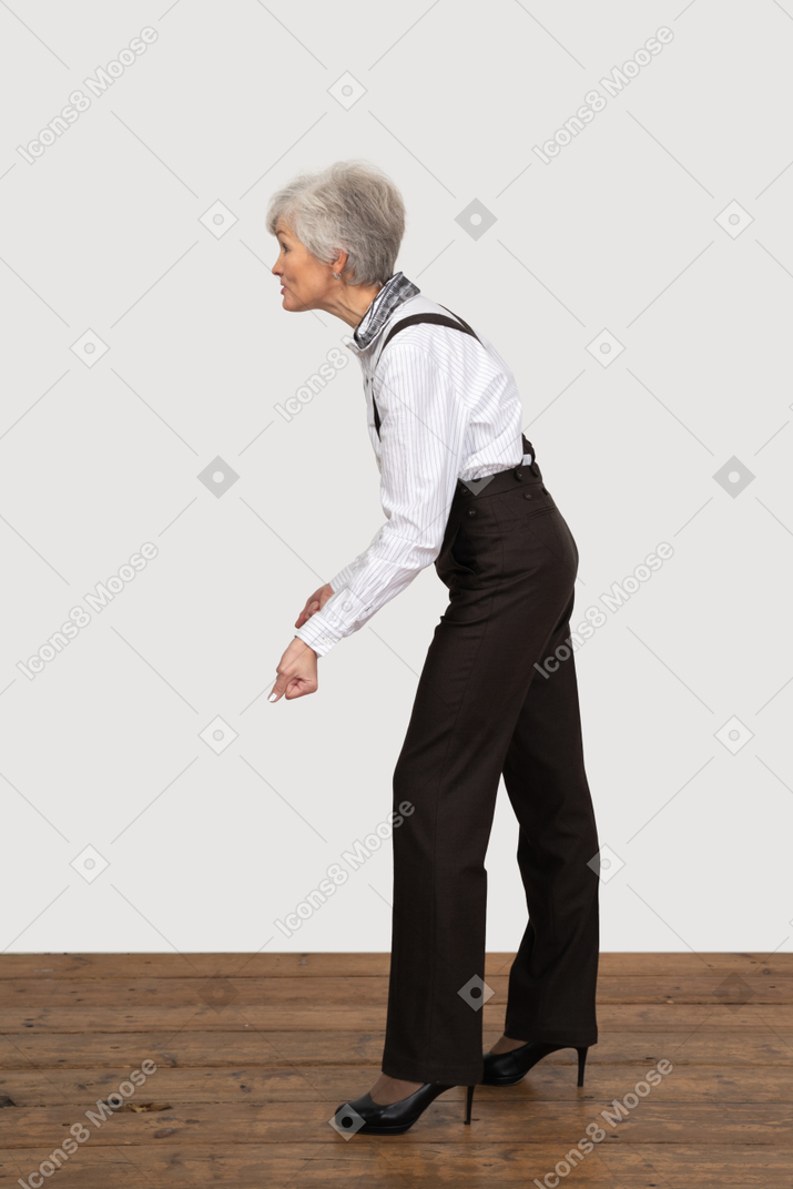 Side view of an old grimacing lady in office clothing clenching her fists