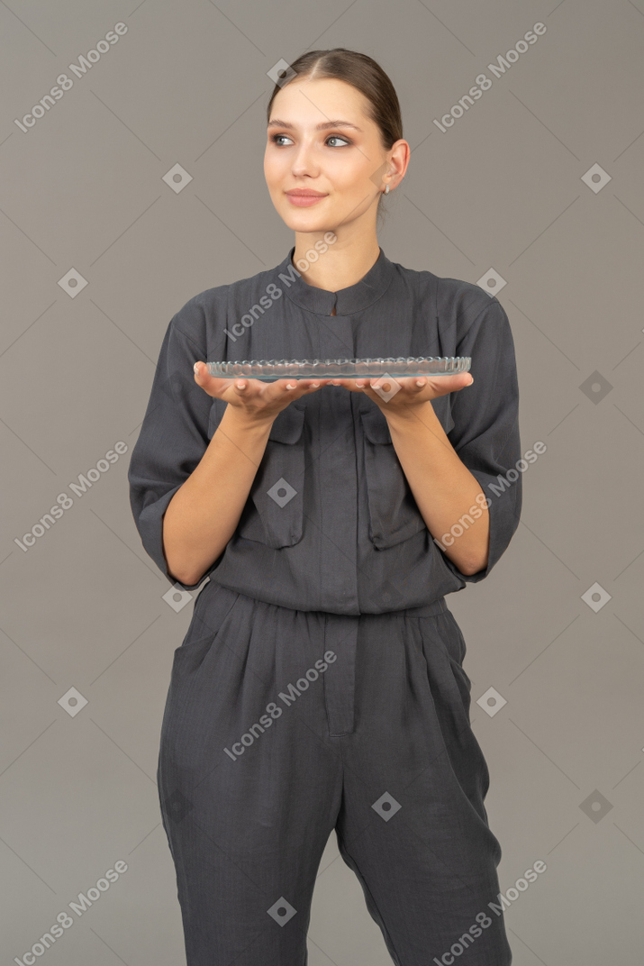 Vista frontale di una giovane donna in tuta che tiene in mano una lastra di vetro