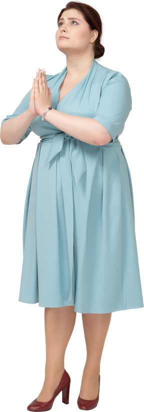 一个穿着蓝色连衣裙的女人做祈祷手势的前视图
