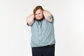 Sad looking young overweight man touching his head with hands