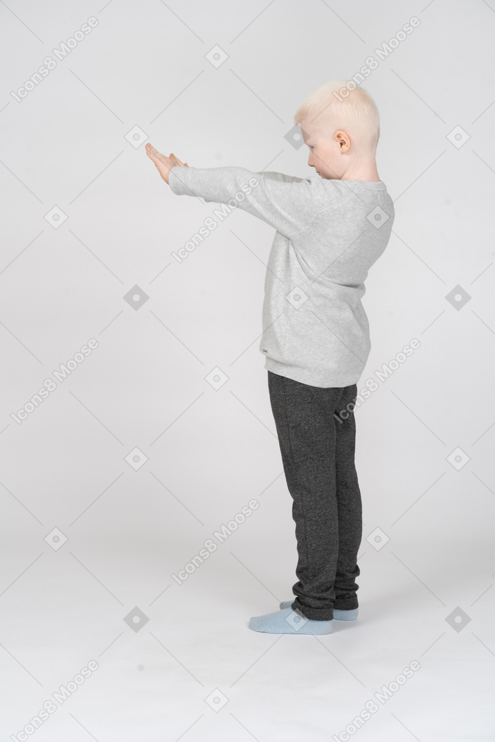 Side view of a little boy with both hands outstretched