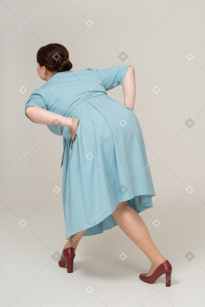 Rear view of a woman in blue dress bending down