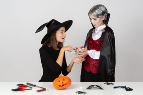 Ragazzo in costume da vampiro che mostra un mucchio di caramelle alla mamma