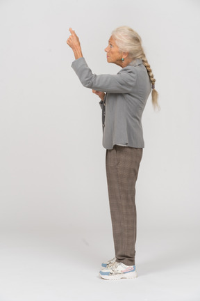 Vista lateral de una anciana en traje apuntando con el dedo