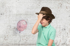 A young boy wearing a green shirt and a brown hat