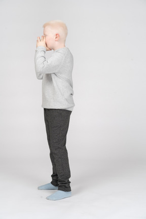 Side view of a boy covering his mouth with hands