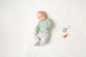 Baby girl lying on the back near toys