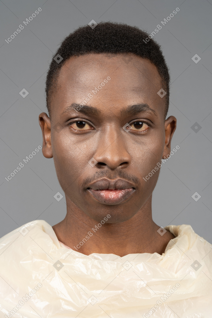 Close-up verticale di un serio uomo africano avvolto in plastica
