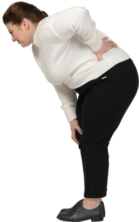 Plus size woman in white sweater suffering from pain in lower back