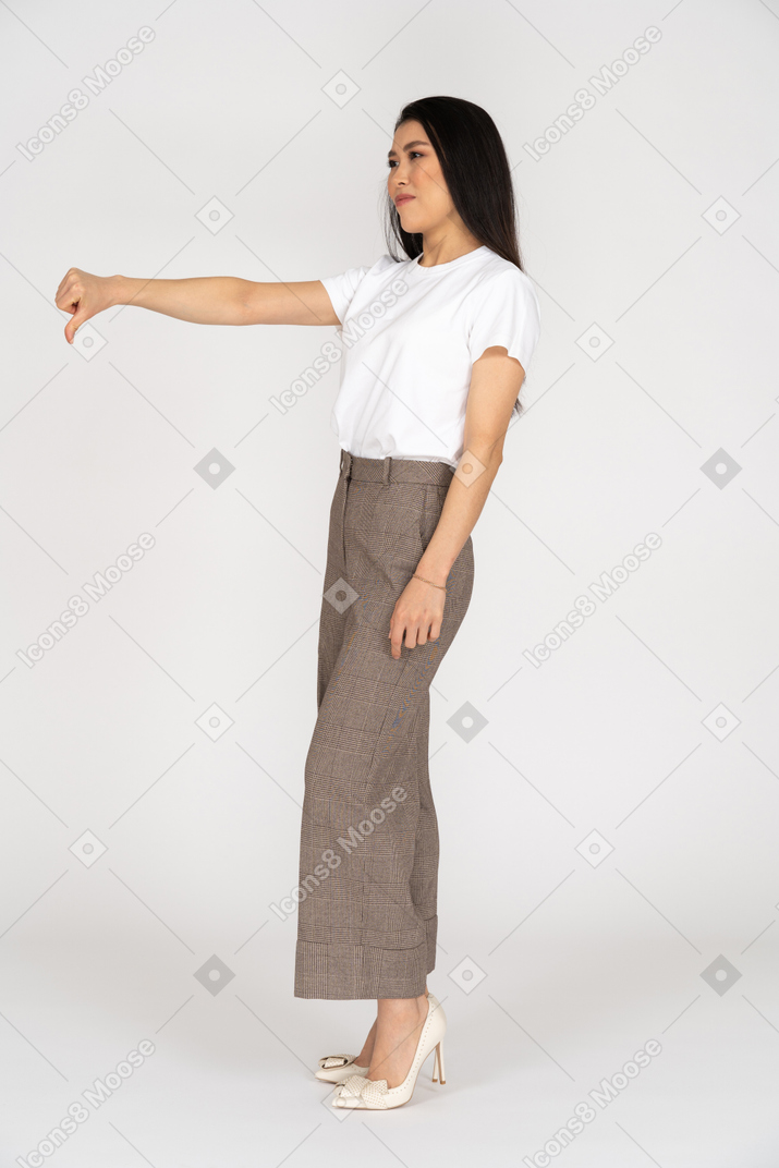 Vista de tres cuartos de una joven en calzones y camiseta mostrando el pulgar hacia abajo