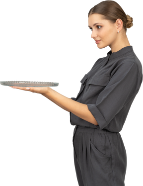 Side view of a young woman in a jumpsuit holding glass plate