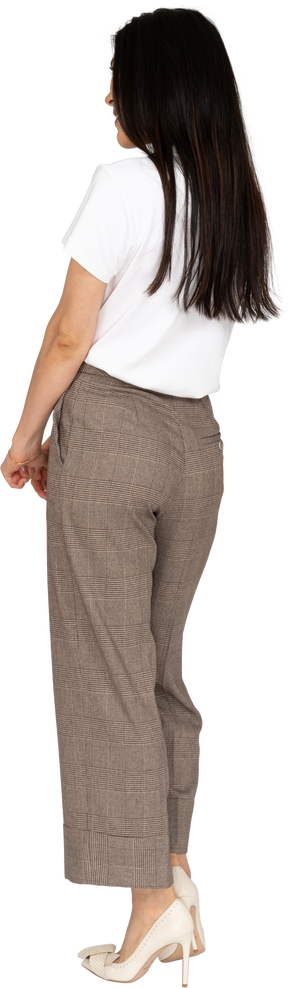Vista posteriore di tre quarti di una giovane donna confusa in calzoni e maglietta che si tengono per mano