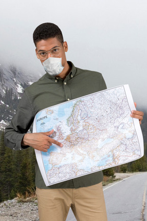 Man in glasses and face mask pointing to a destination on the map