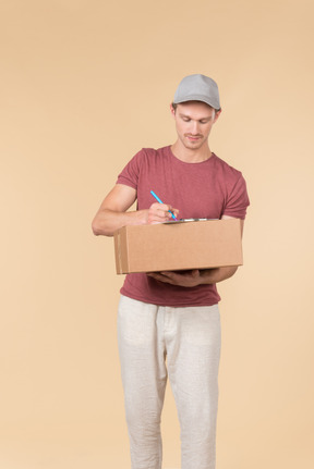 Delivery guy holding box and writing something down in the folder