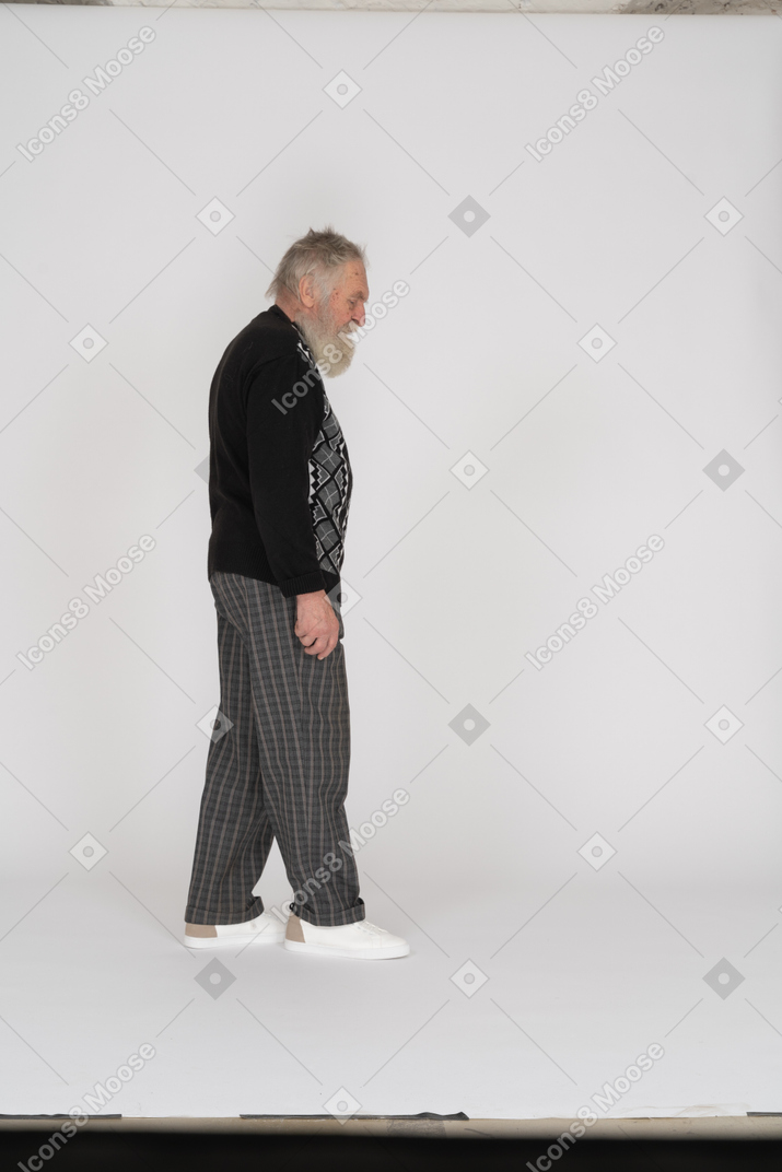 一位老人走路和向下看的侧视图