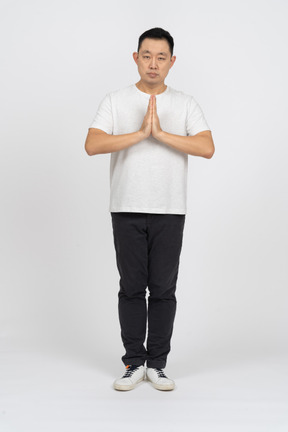 Front view of a man in casual clothes making praying gesture and looking at camera