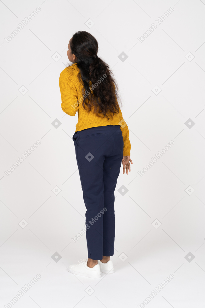 Rear view of a girl in casual clothes standing with hand on chest