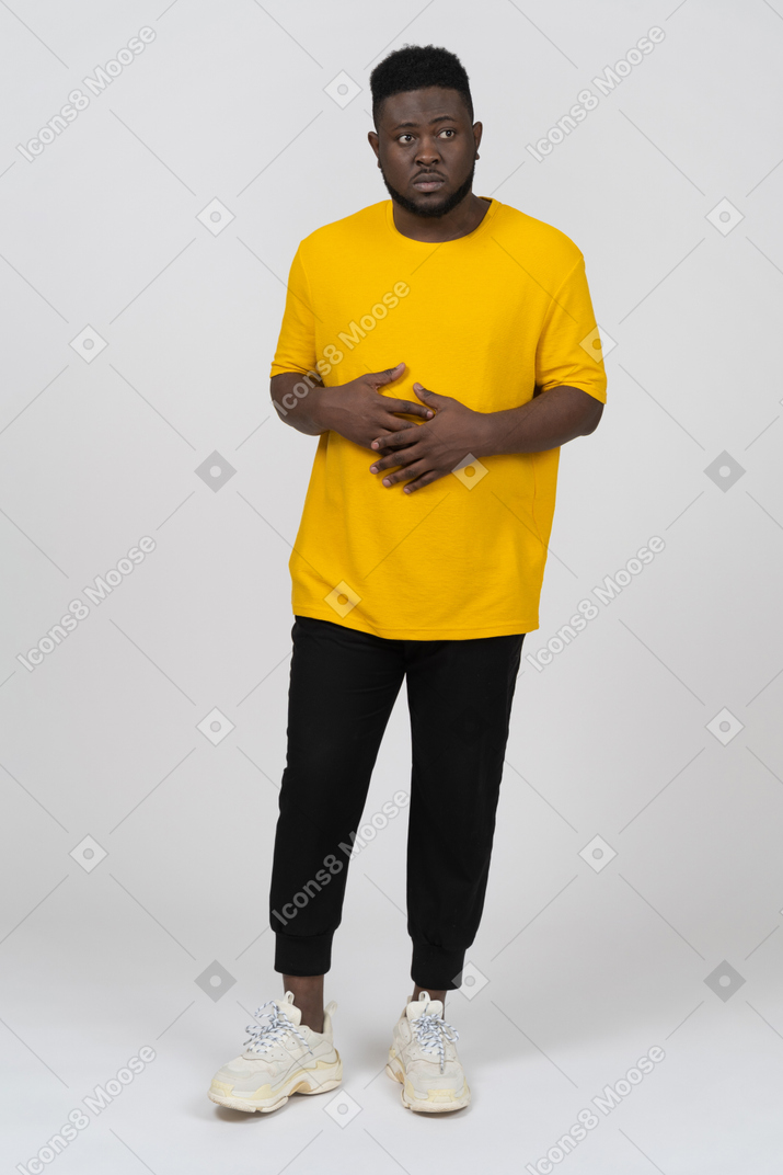 Vue de face d'un jeune homme à la peau foncée en t-shirt jaune tenant les mains sur le ventre