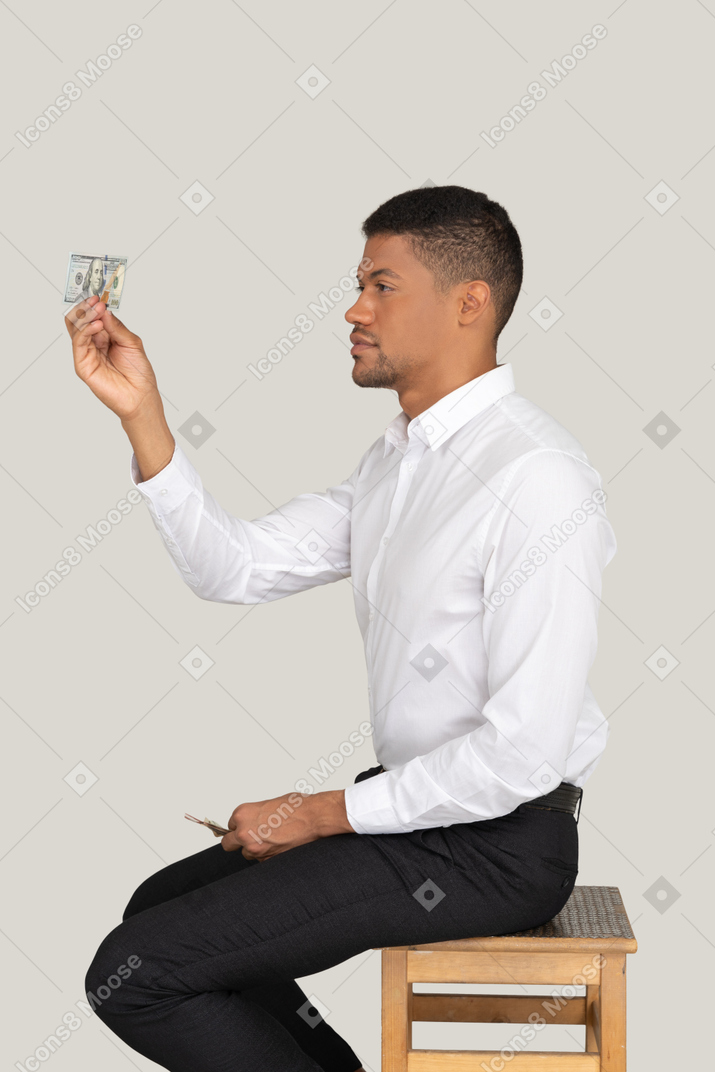 A man sitting on a chair holding a stack of money