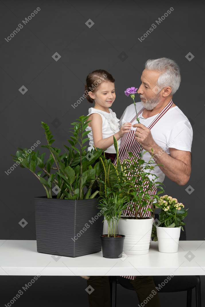 家の植物の横にある彼の手に小さな女の子を保持している成熟した男