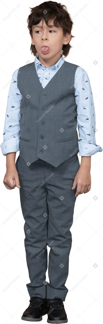 Vista frontale di un ragazzo carino in abito grigio che mostra la lingua e guarda da parte