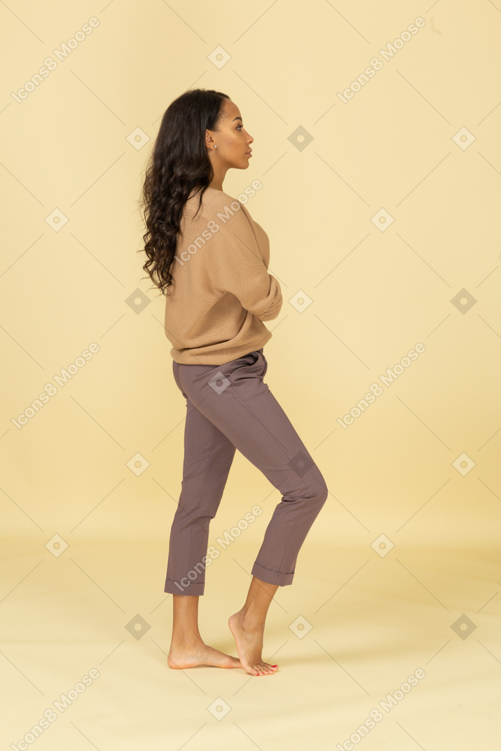 Vista lateral de uma jovem mulher de pele escura cruzando os braços