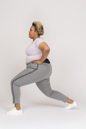 Plump african-american woman doing forward lunges