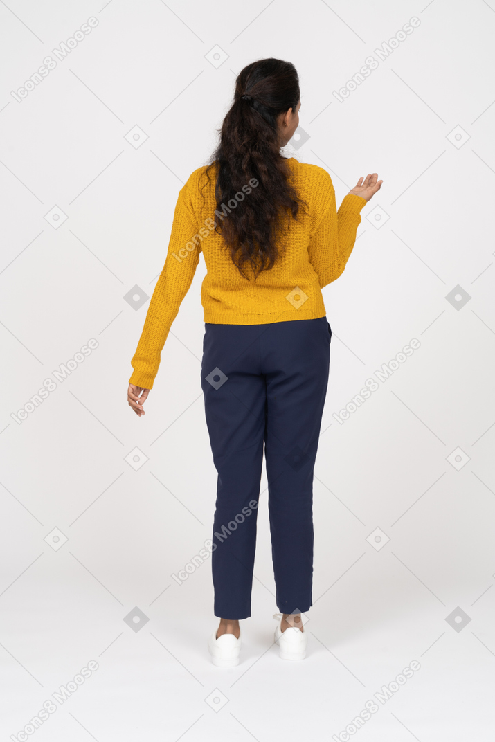 Rear view of a girl in casual clothes standing with raised hand