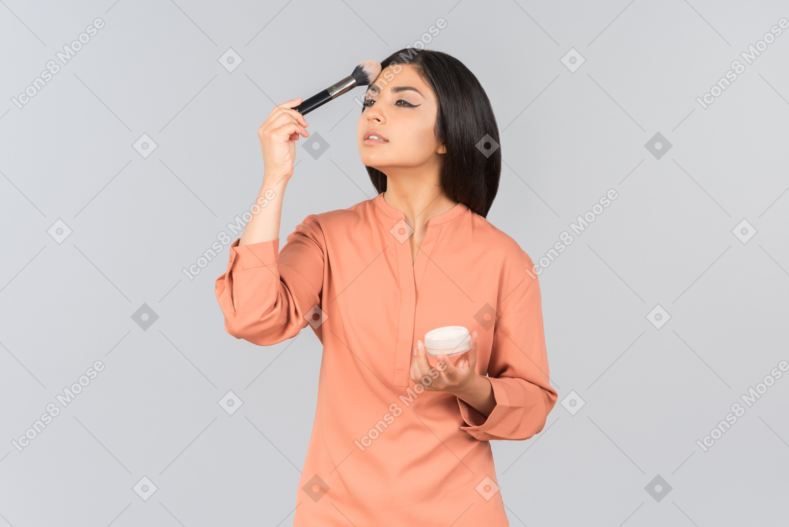 Mujer india aplicando polvos para la cara en la frente