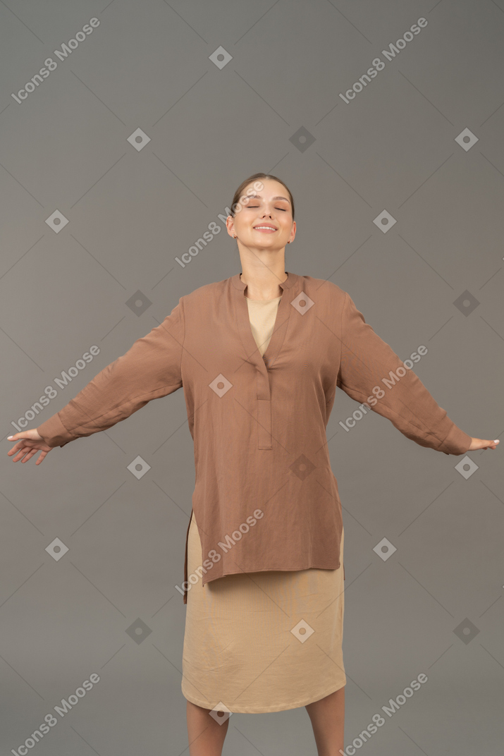 Eyes closed woman standing with her arms and legs wide open