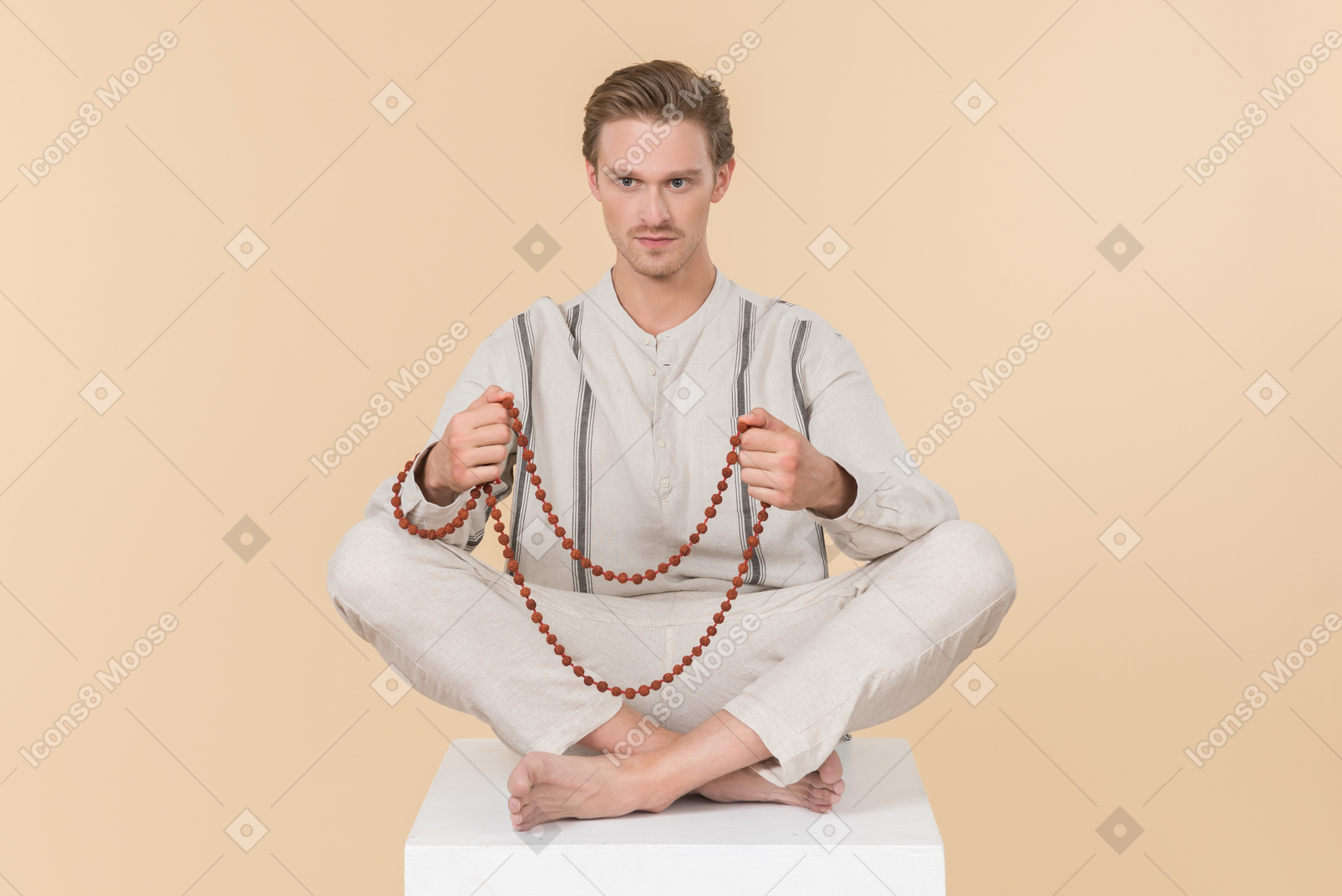 Young caucasian man with necklace sitting in lotus pose with his eyes closed