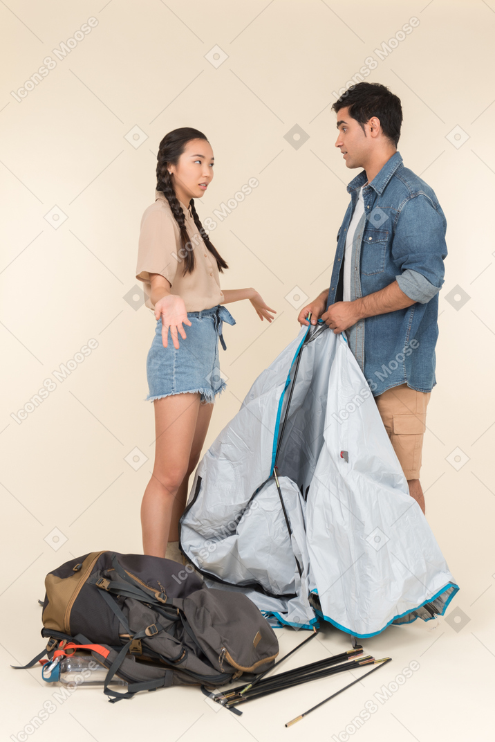 Young interracial couple arguing while setting up a tent