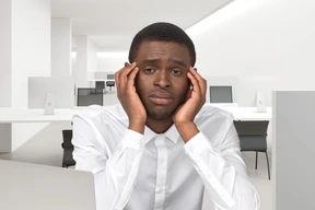 An unhappy looking man sitting in front of a laptop at the office