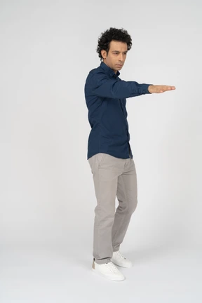 Front view of a man in casual clothes pointing with hand