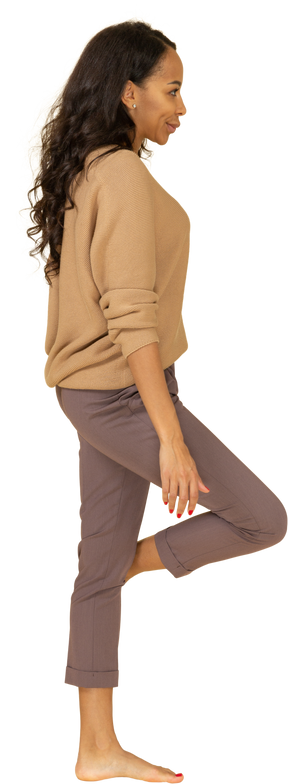 Vista lateral de uma jovem mulher de pele escura fazendo beicinho levantando a perna