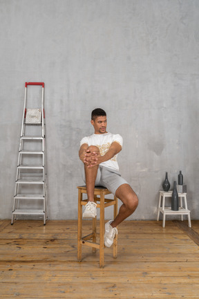 Man sitting with hands on his knee and looking aside