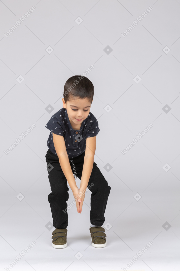 Front view of a cute boy bending down with extended arms