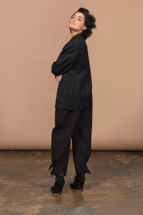 Vista traseira de uma empresária em um terno preto se virando e olhando para a câmera
