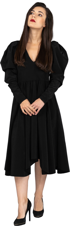 Vista frontal de uma jovem em um vestido preto de mãos dadas