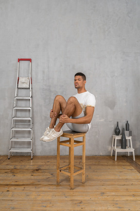 Man sitting on chair and hugging his knees in