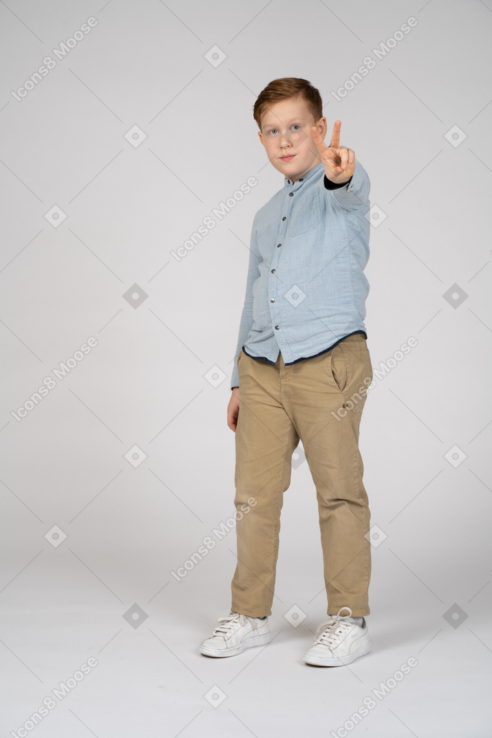 Front view of a boy showing v sign and looking at camera
