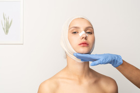 Young woman with bandaged head and gloved hand under her face